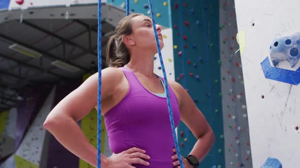 Nervous caucasian woman preparing to climb a wall at indoor climbing wall