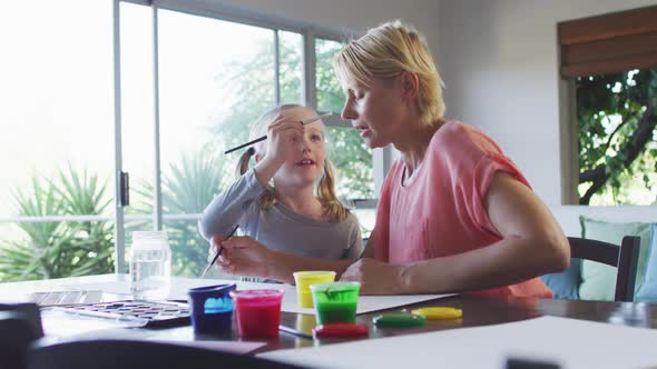 Side view of Caucasian woman painting with her daughter at home