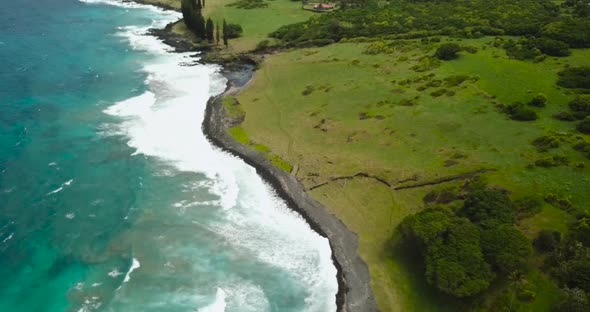 Drone above a blue beach. Pans down to the waves crashing.