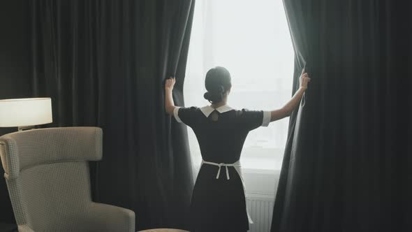 Female Housekeeper Opening Curtains in Hotel Room