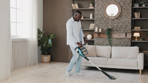 Adult African American Homeowner Cleaner Washing Floor Parquet Surface with Vacuum Cleaner in