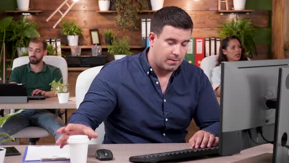 Portrait of a Businessman Sipping Coffee and Typing on the Computer