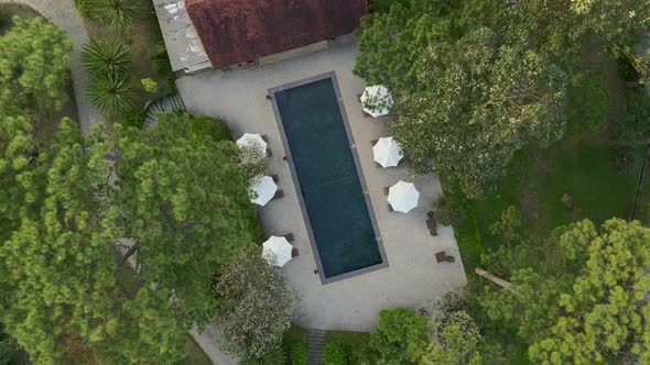 Aerial drone flying above of a beautiful swimming pool under sunshine reveal landscape of resort on