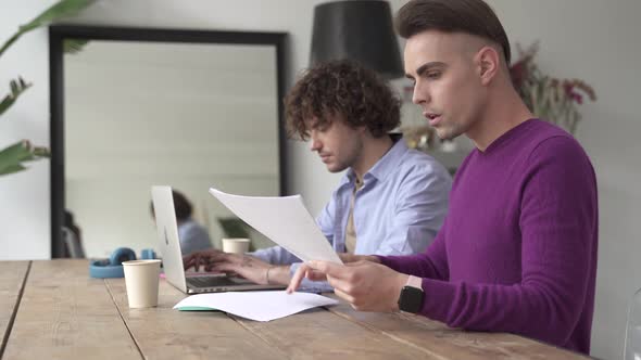 Male Gay Couple Working Doing Finances and Paperwork at Home Calculating Budget for Domestic Life