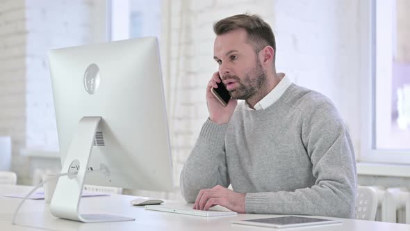 Creative Man Talking on Smartphone at Work