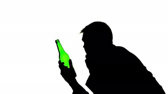 Alcoholic Sits with a Bottle in His Hands and Drinks, Side View, Silhouette White Background