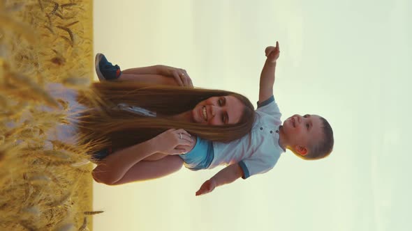 Vertical Screen Little Boy on Shoulders of Mom Walking in Field