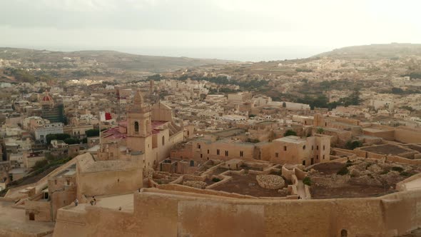 Gozo Castle Fort with Malta Flag Waving Castle in Beautiful Sand Brown Color, Aerial Slide Right