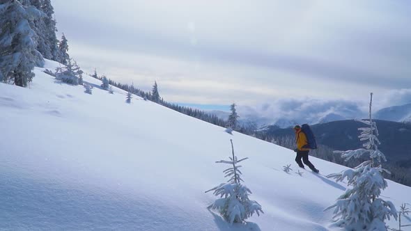 Tourist with a Backpack Climbs the Snowy Slope