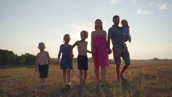 A Friendly Large Family Walks Across the Field at Sunset