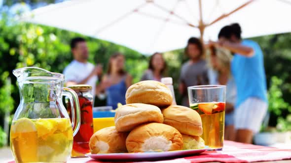 Close-up of juice and buns served on table at outdoors barbecue party