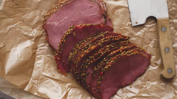 Delicious Peppered Roast Beef Pastrami Slices on Paper with Grains of Coloured Pepper