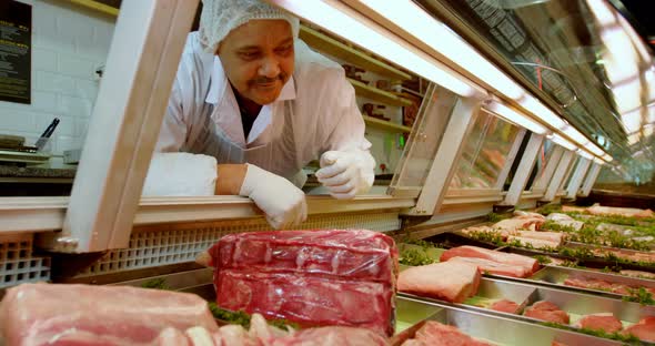 Butcher arranging meat in refrigerator