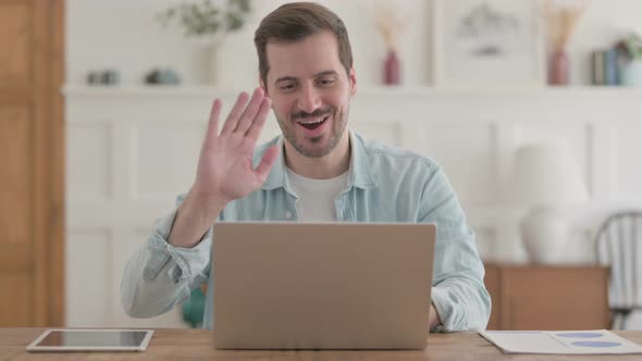 Young Man Talking on Video Call on Laptop in Office