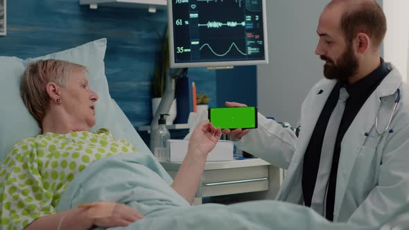 Retired Patient Looking at Horizontal Green Screen on Phone