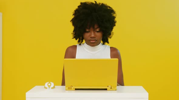 AfroAmerican Woman Uses Yellow Laptop
