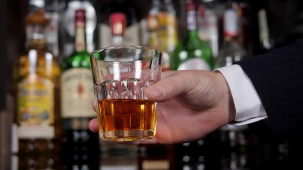 Close Up of Man's Hand Holding Crystal Glass of Whiskey or Brandy