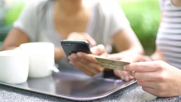 Women using smartphone and credit card to complete online transaction