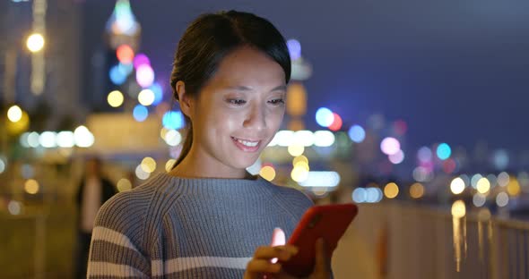 Woman work on smart phone in city at night