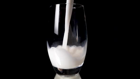 Pouring vegan rice milk in a glas in slow motion on a shiny, reflective underground.