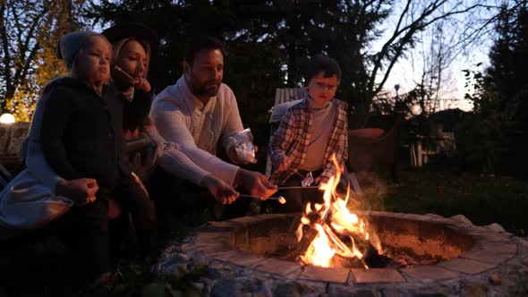 Portrait of a Happy American Family. They Sit Around the Fire and Roast Marshmallows