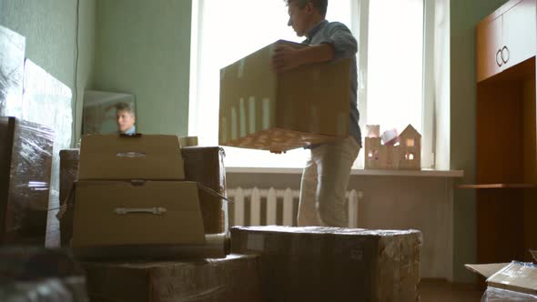 Millennial Male Renter in Living Room Holding Tape Dispenser Sealing Cardboard Boxes Moving to New