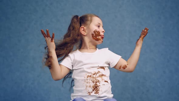 Funny little girl in smeared chocolate on face and hands. 