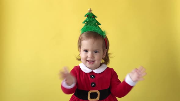 Portrait Emotion Happy Chubby Toddler Baby Girl In Santa Suit Smiling Applaud With Christmas Tree on