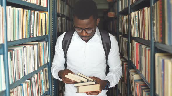 Young Arabian Bearded Male Student Choosing Book Between Shelves in the Library