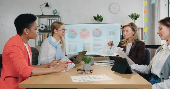 Business Women Sitting at Office Desk, Discussing Schedules and New Project Ideas