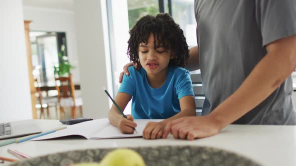 Happy biracial man and his son doing homework together