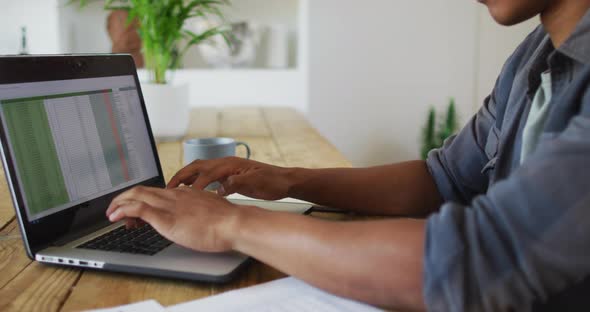 African american man working from home and using laptop