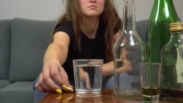 woman is suffering from hangover, she throws painkiller pill into glass of water