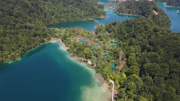 View of the Plitvice Lakes National Park with many green plants and blue lakes and waterfalls drone