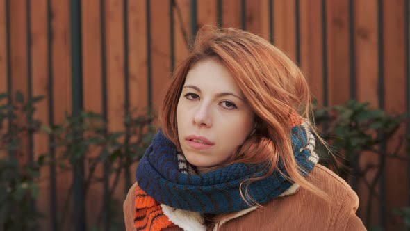 Confident serious red haired woman alone,looking at camera in winter day