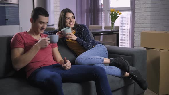 Couple Watching TV After Unpacking Boxes