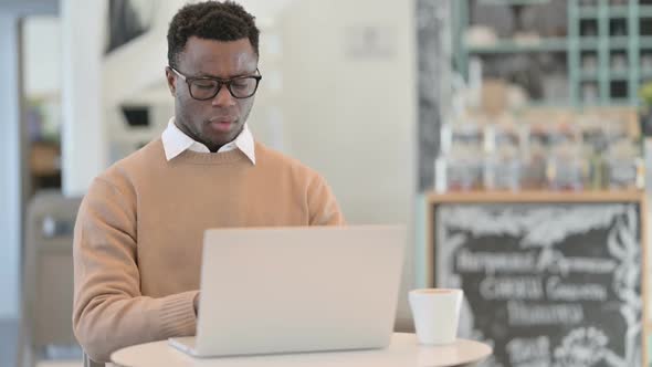 Creative African Man Coughing While Using Laptop in Cafe