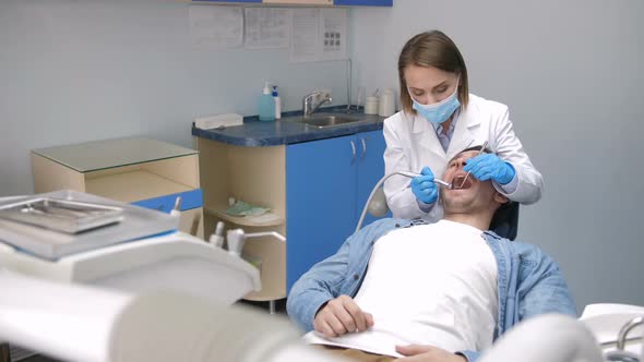 Female Dentist Treating Client's Teeth at Clinic