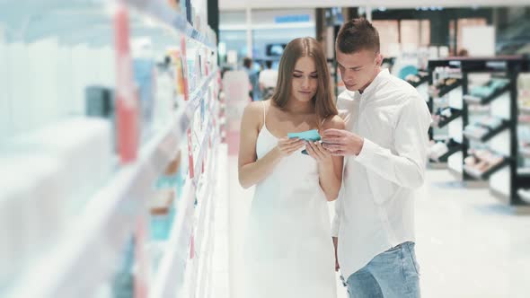 Girl and a Handsome Guy Discussing a Novelty in Perfumery While Shopping