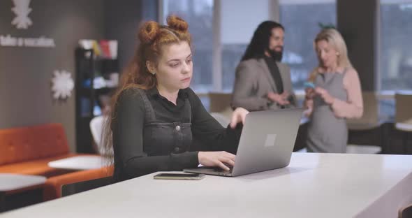 Portrait of Exhausted Redhead Caucasian Woman Typing on Laptop Keyboard and Holding Head with Hand