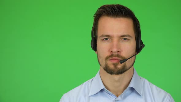 A Young Handsome Call Center Agent Looks Seriously at the Camera - Closeup - Green Screen Studio