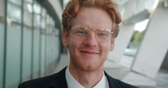 Close Up Attractive Red Haired Man in Business Suit Wearing Spectacles and Looking Into Camera with