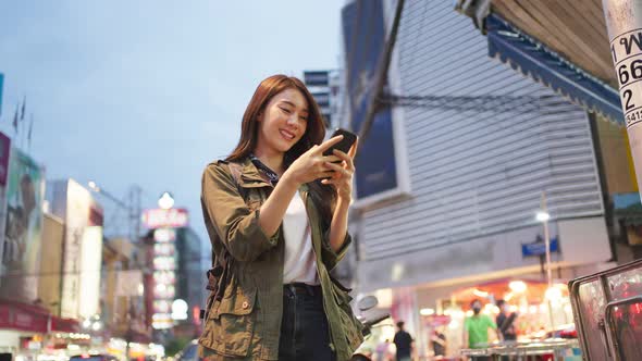 Asian attractive woman backpacker chatting on phone while walk in city.