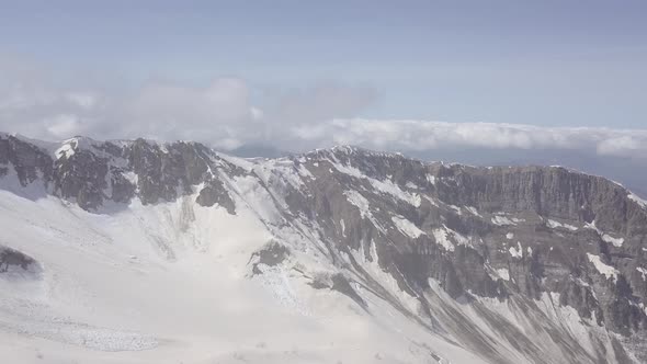 Aerial view of snowy peaks of rocky Caucasus mountains, Krasnaya Polyana, Sochi, Russia. Blue sky