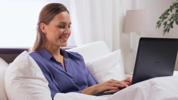 Young Woman with Laptop in Bed at Home Bedroom