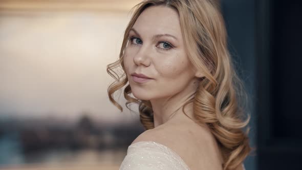 A Blonde Woman with Blue Eyes and Styled Hair Turning Around Her Shoulder