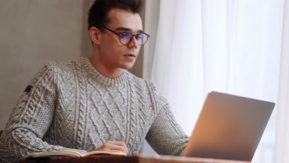 Laughing man wearing eyeglasses talking by video call on laptop