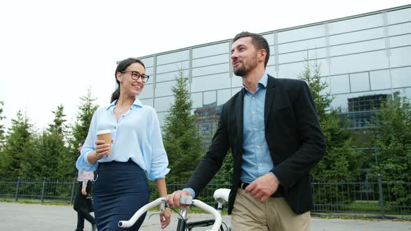 Businessman and Businesswoman Talking Walking From Work, Guy Is Holding Bike