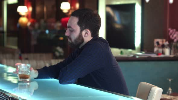 Cheerful Attractive Young Man Drinking in in a Bar and Look at Camera Smiling