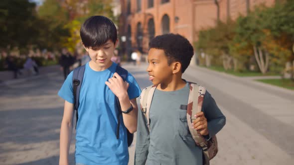 Two Diverse School Kids Walking Home Together After School and Talking
